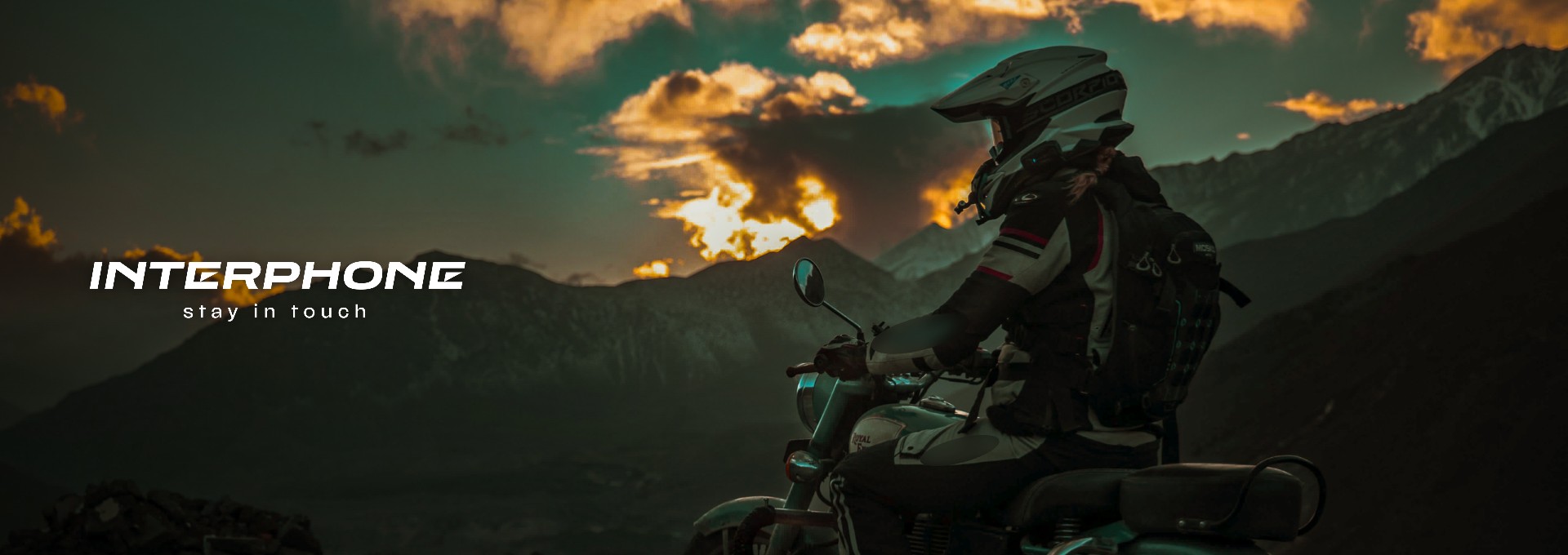 Interphone Header Motorradfahrer mit Interphone-Kommunikationssystem vor Bergkulisse im Sonnenuntergang